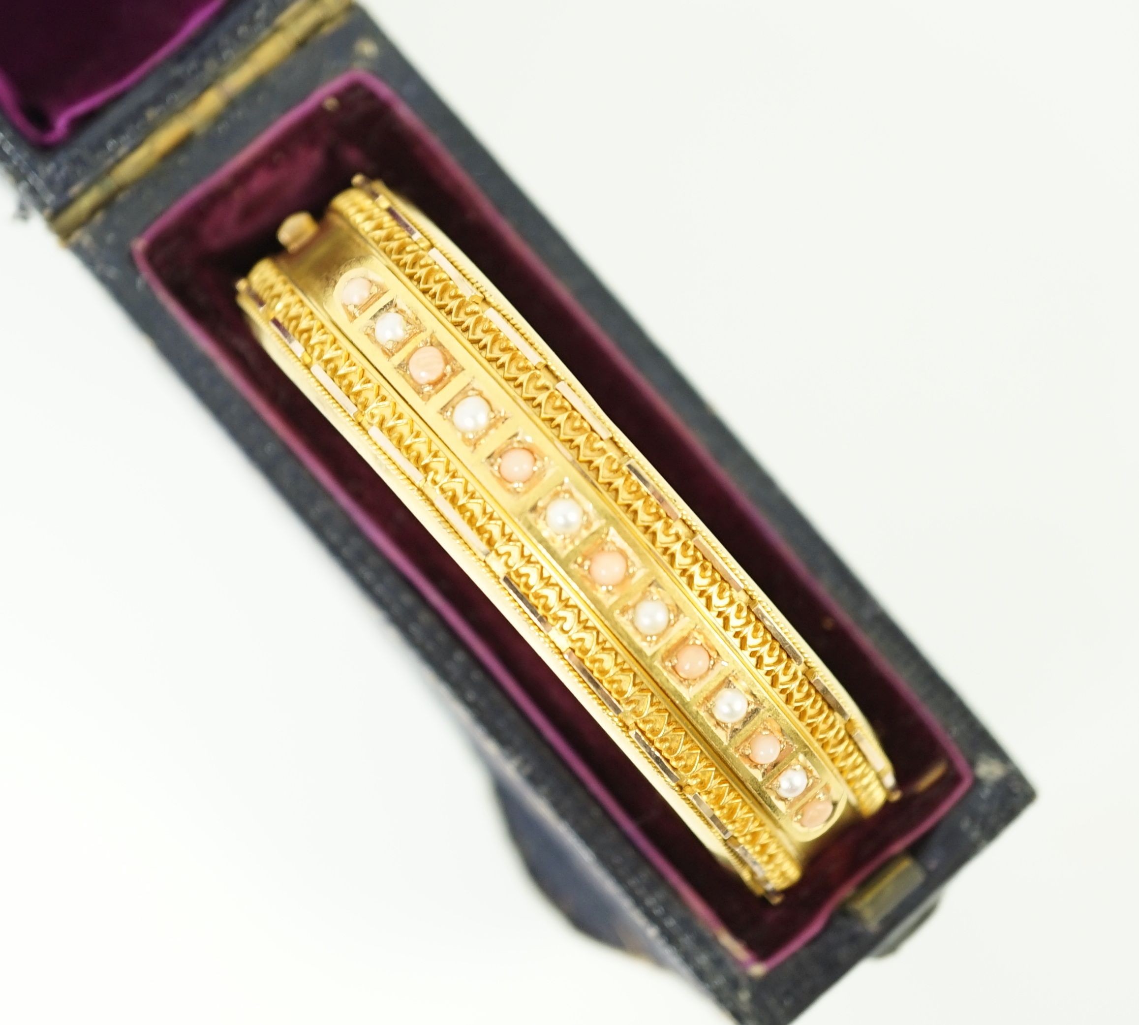 A late Victorian 15ct gold coral bead and seed pearl set part cannetile work hinged bangle